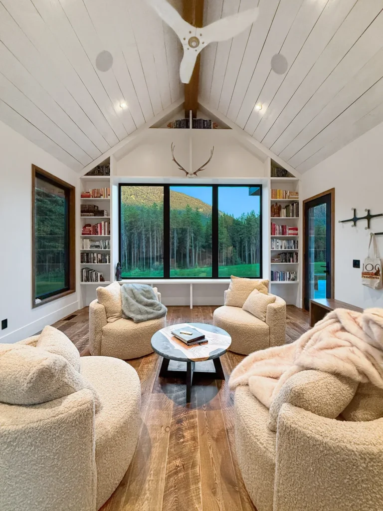 A living room at Halfmoon Camp with mountain views through full height windows