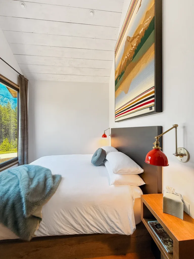 A bedroom at Halfmoon Camp with white bedding and a reading lamp